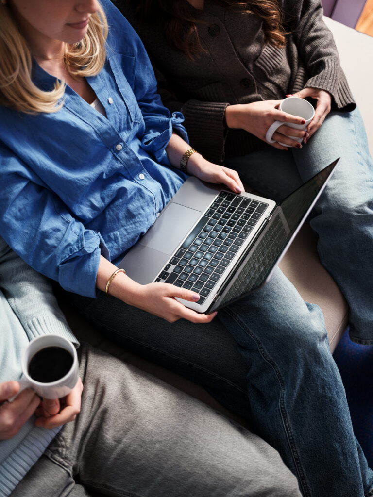 Tre personer som sitter vid en laptop